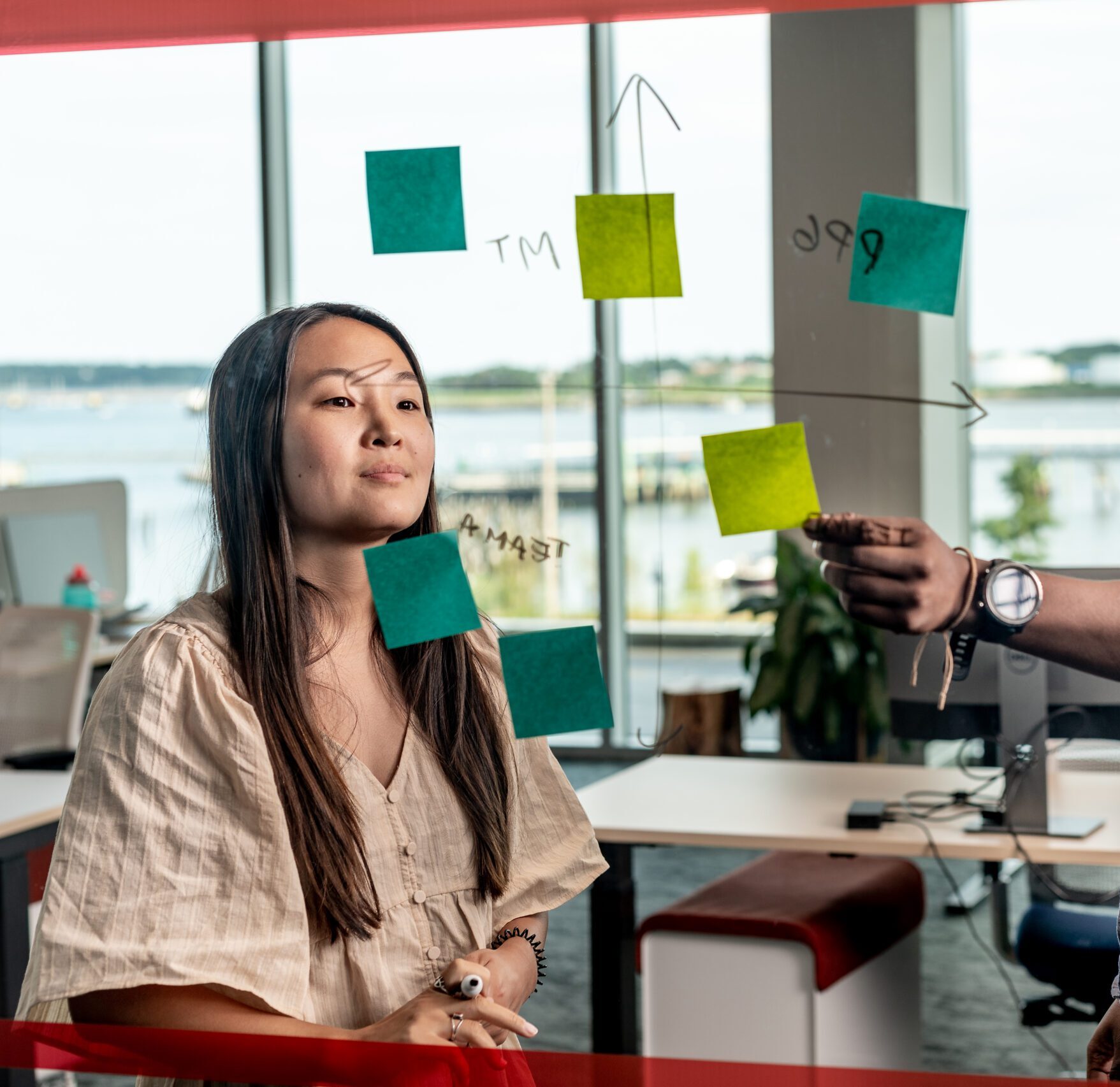 a woman looking at a man writing on a glass wall